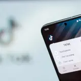 Telefon z aplikacją TikTok, gdzie widać opcję "Clear cache" (wyczyść pamięć podręczną), by przyspieszyć działanie.