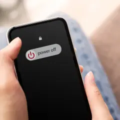 Dłoń trzyma telefon z ekranem blokady, na którym widnieje przycisk "power off". Dowiedz się, jak wyłączyć telefon realme.
