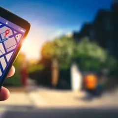 Dłoń trzyma smartfon z mapą i trasą. Dowiedz się, jak włączyć nawigację w telefonie, by łatwo dotrzeć do celu.