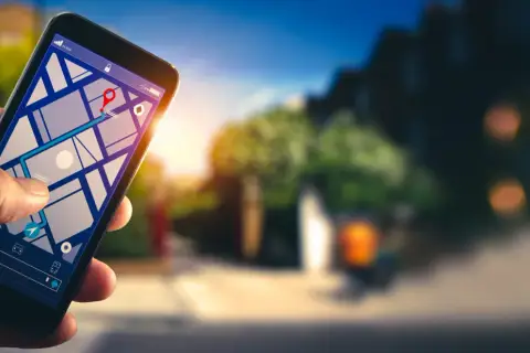 Dłoń trzyma smartfon z mapą i trasą. Dowiedz się, jak włączyć nawigację w telefonie, by łatwo dotrzeć do celu.