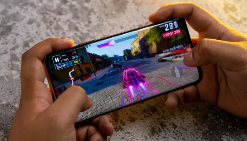 Ręce trzymają smartfon, na którym gra wyścigowa. Ten telefon do 2500 zł świetnie radzi sobie z grafiką.