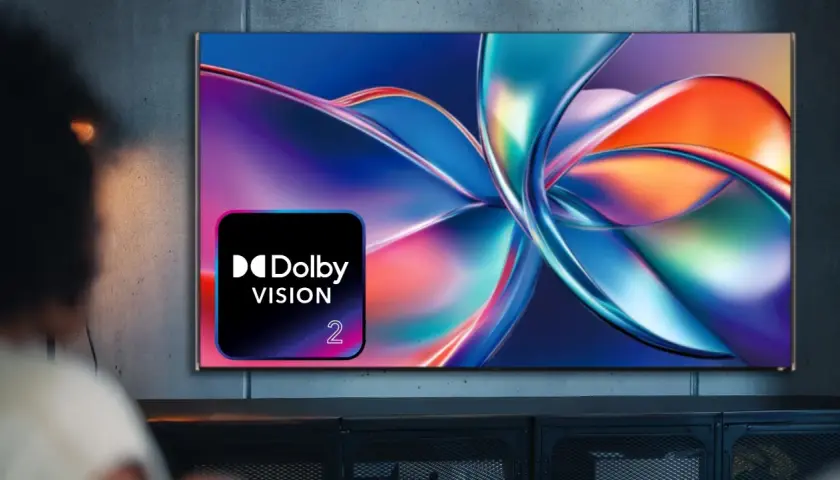 Osoba ogląda telewizor z logo Dolby Vision, wyświetlający abstrakcyjny, kolorowy obraz.