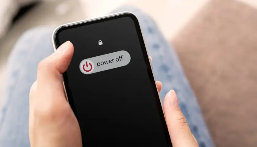 Dłoń trzyma telefon z ekranem blokady, na którym widnieje przycisk "power off". Dowiedz się, jak wyłączyć telefon realme.