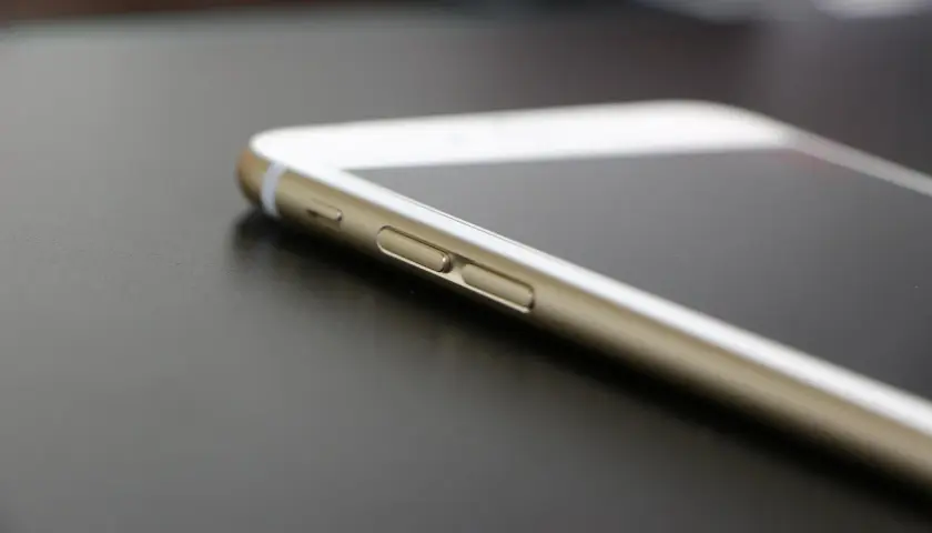 Złoty telefon leży na ciemnym blacie. Dowiedz się, jak sprawdzić lokalizację telefonu, by mieć pewność, że jest bezpieczny.