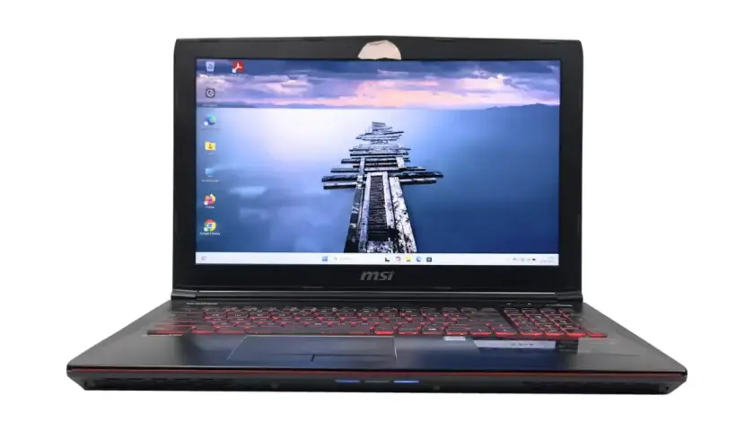 Czarny laptop MSI z podświetlaną na czerwono klawiaturą. Na ekranie widok na drewniane molo. Zastanawiasz się, jaki Windows do starego laptopa?