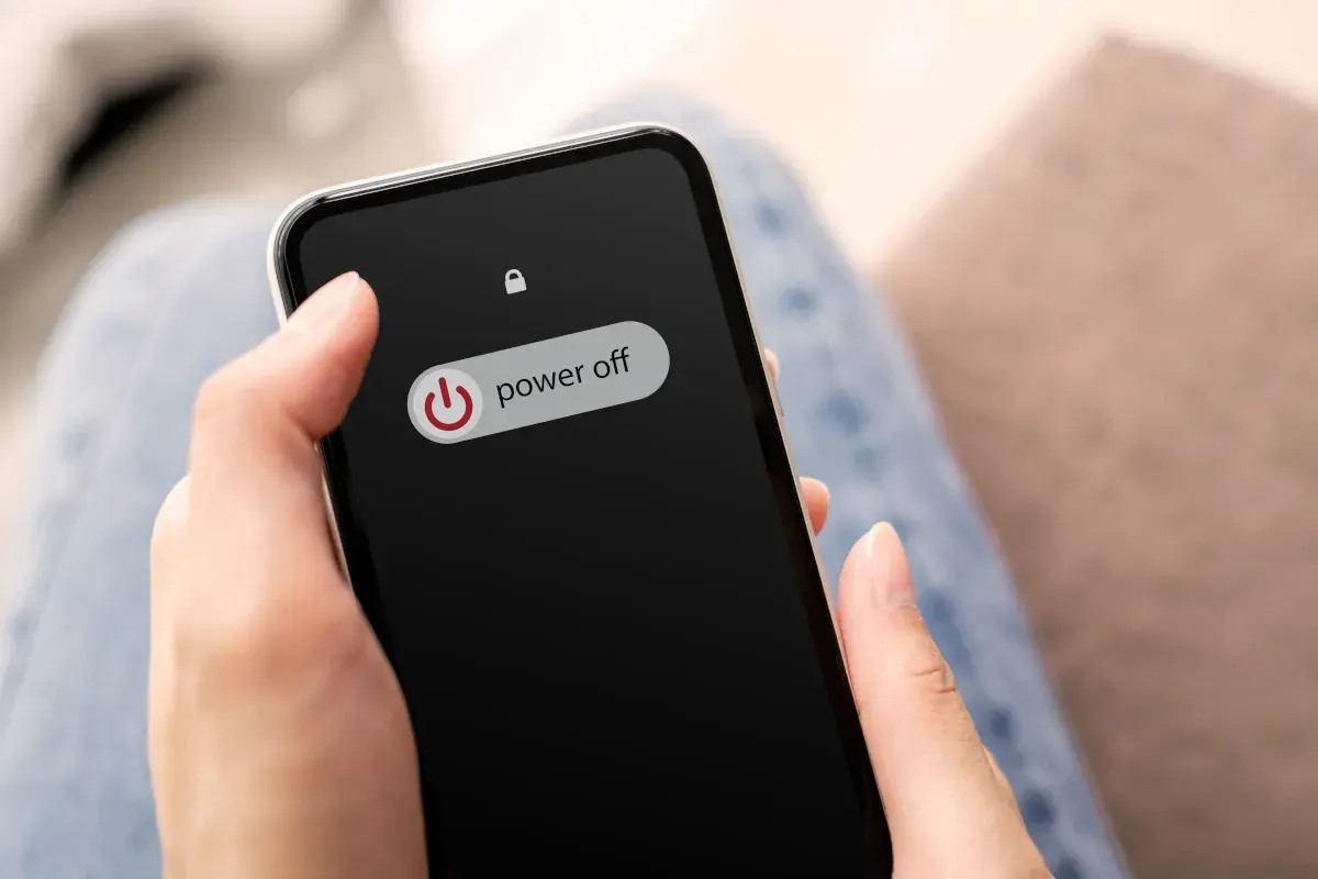 Dłoń trzyma telefon z ekranem blokady, na którym widnieje przycisk "power off". Dowiedz się, jak wyłączyć telefon realme.