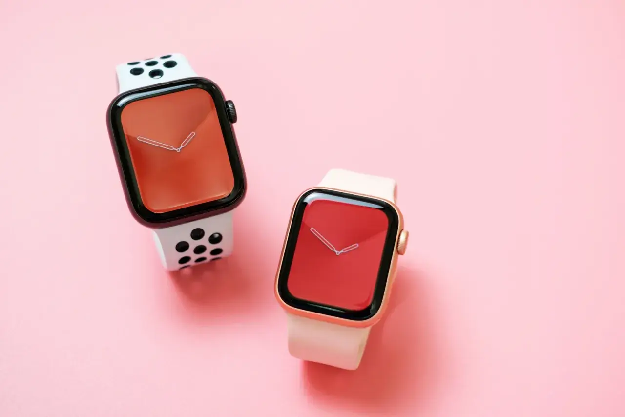 Dwa zegarki Apple Watch na różowym tle. Jeden z białym paskiem w czarne kropki, drugi z jasnoróżowym. Czas na wymiana baterii Apple Watch.